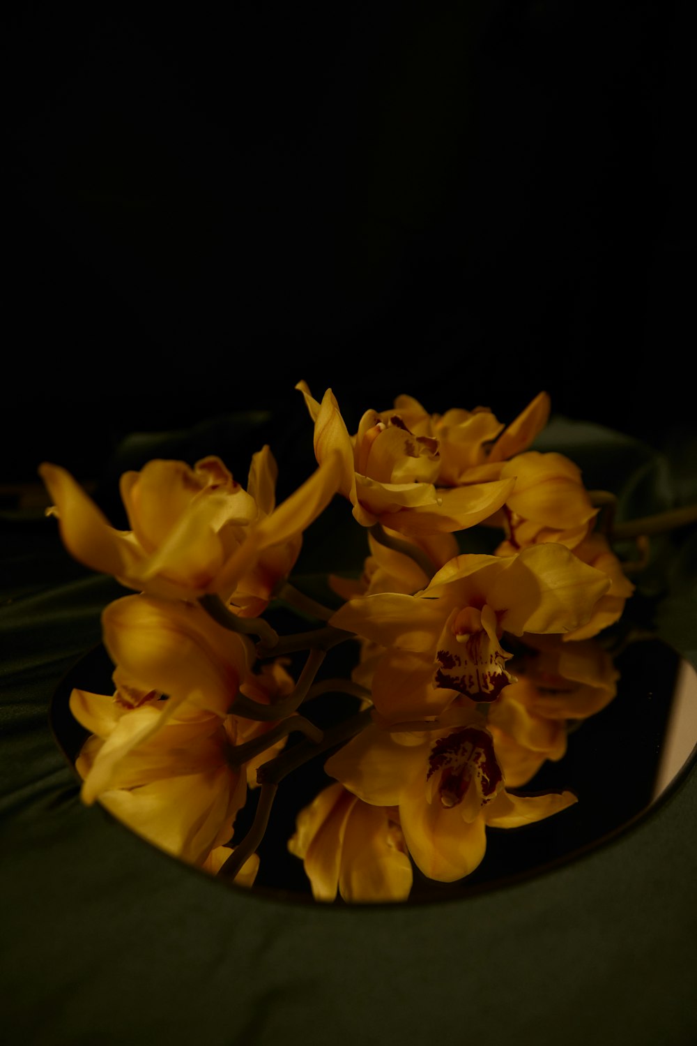 ein schwarzer Teller mit gelben Blumen auf einem Tisch