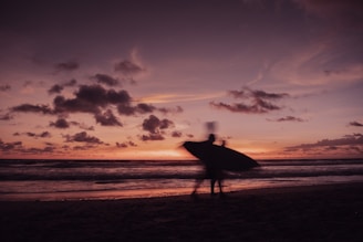 a person standing on a beach holding a surfboard