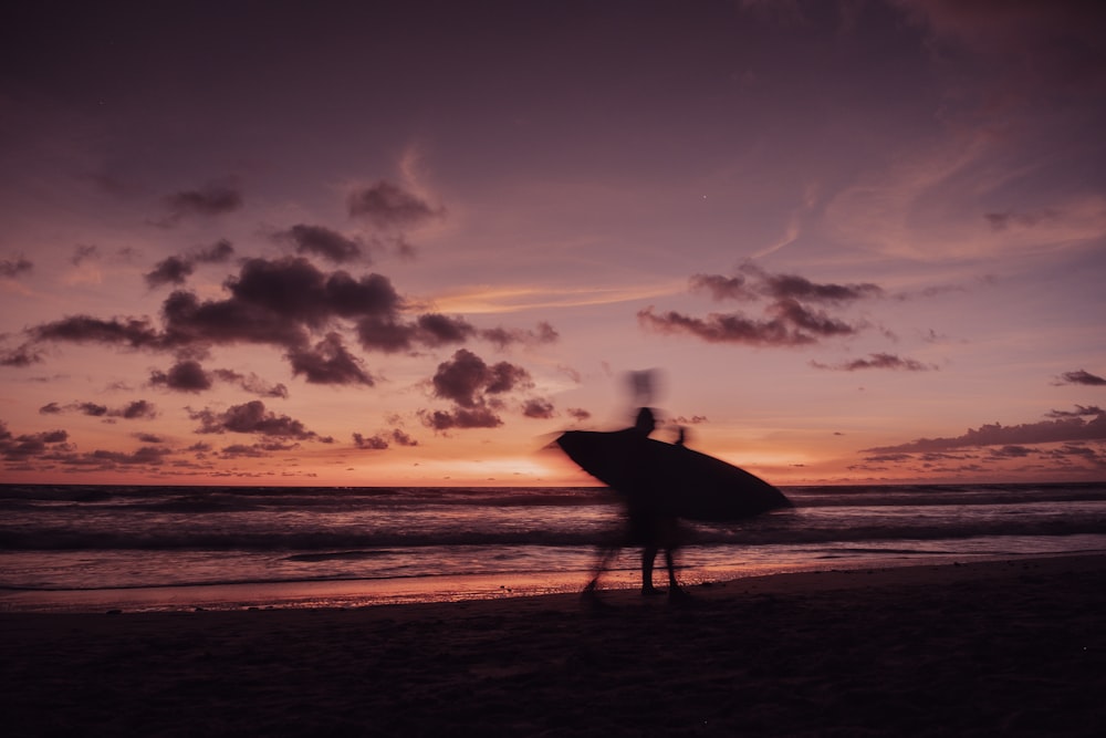 a person standing on a beach holding a surfboard