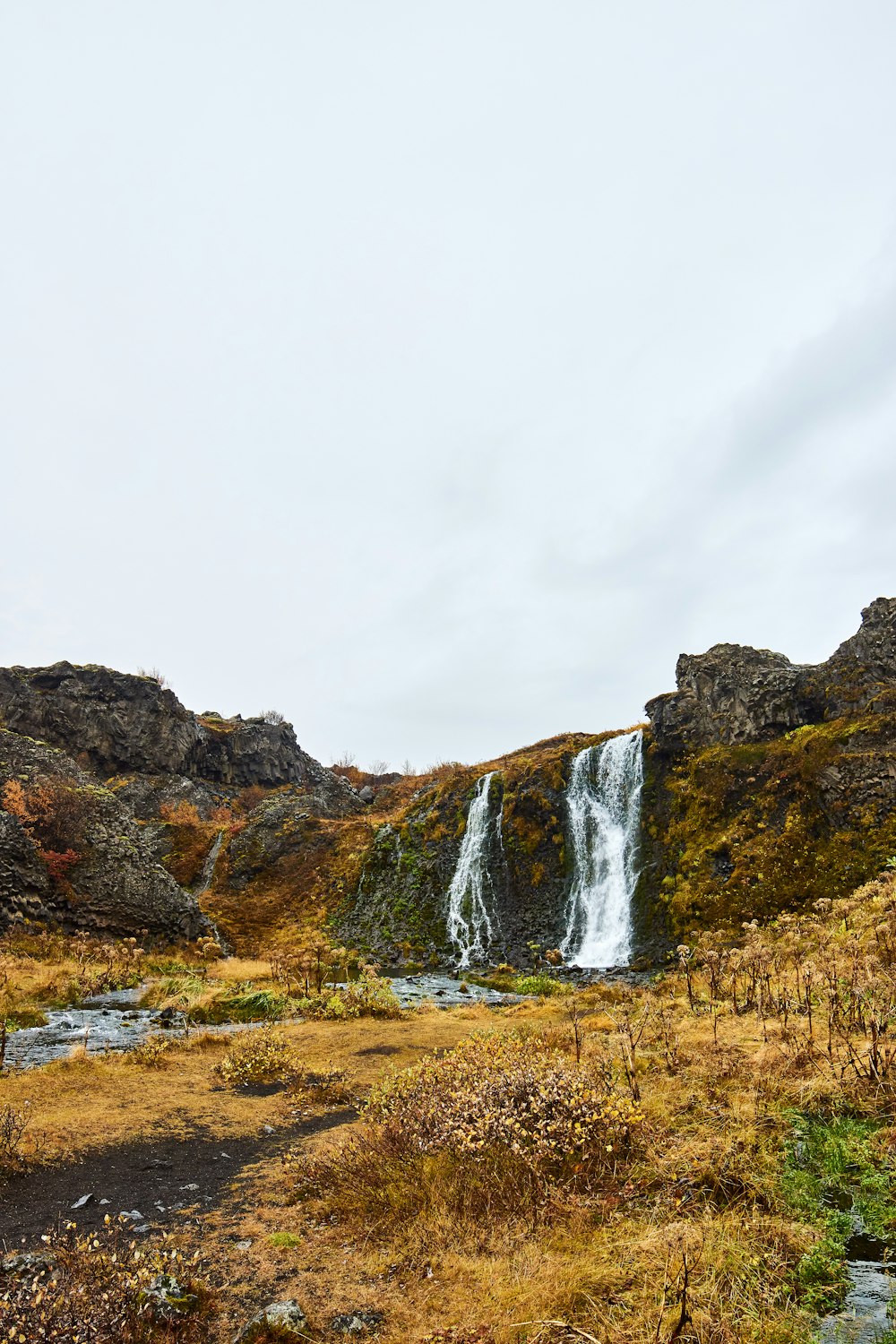 a waterfall in the middle of a grassy field