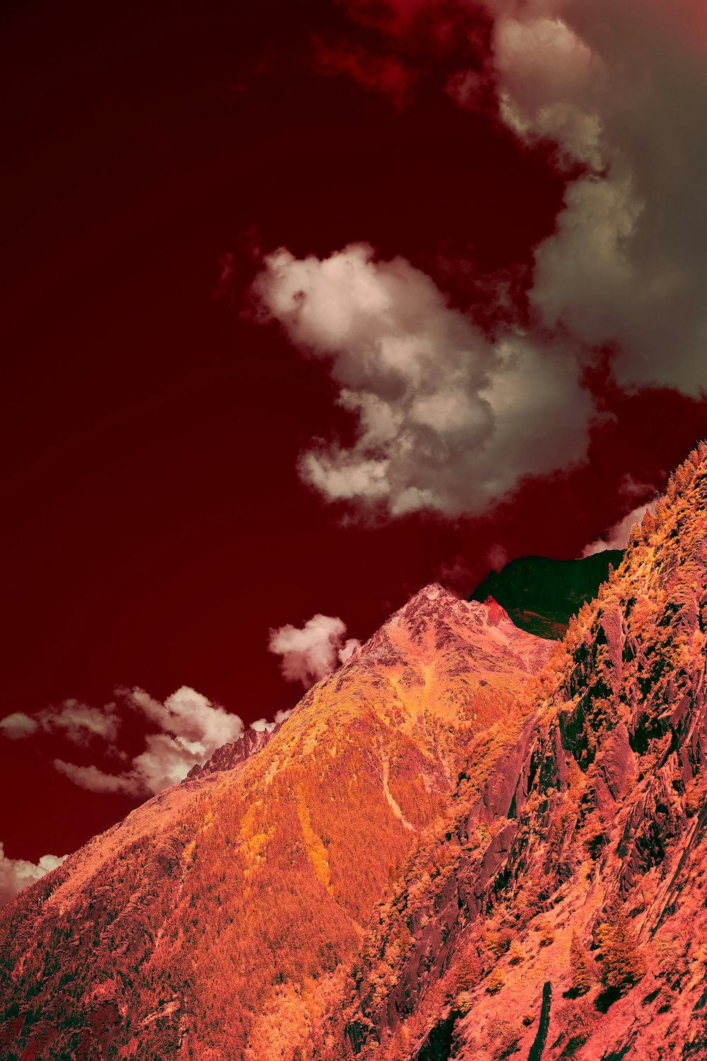 a mountain with a red sky and clouds in the background