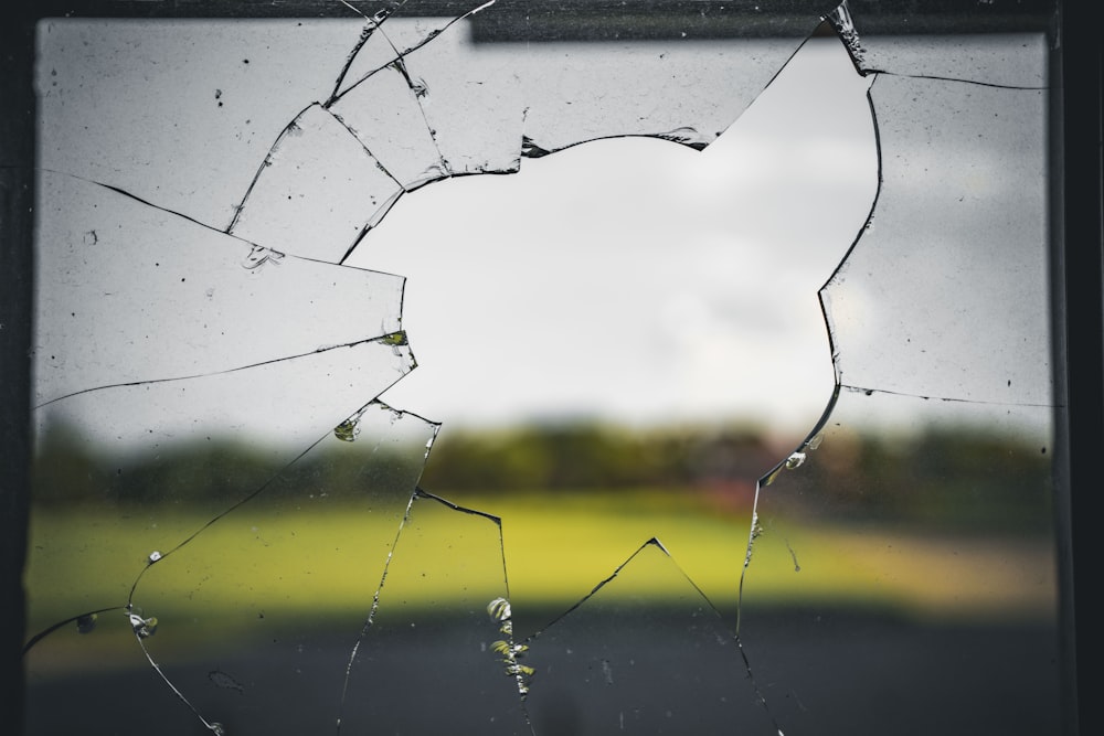 a broken glass window with a field in the background