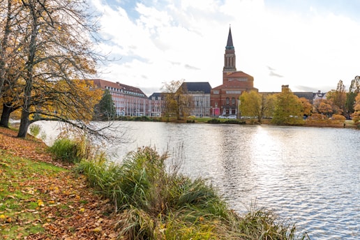 a lake in front of a building with a clock tower