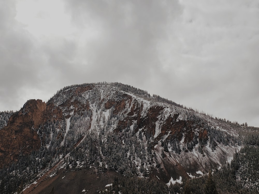 a mountain covered in snow under a cloudy sky