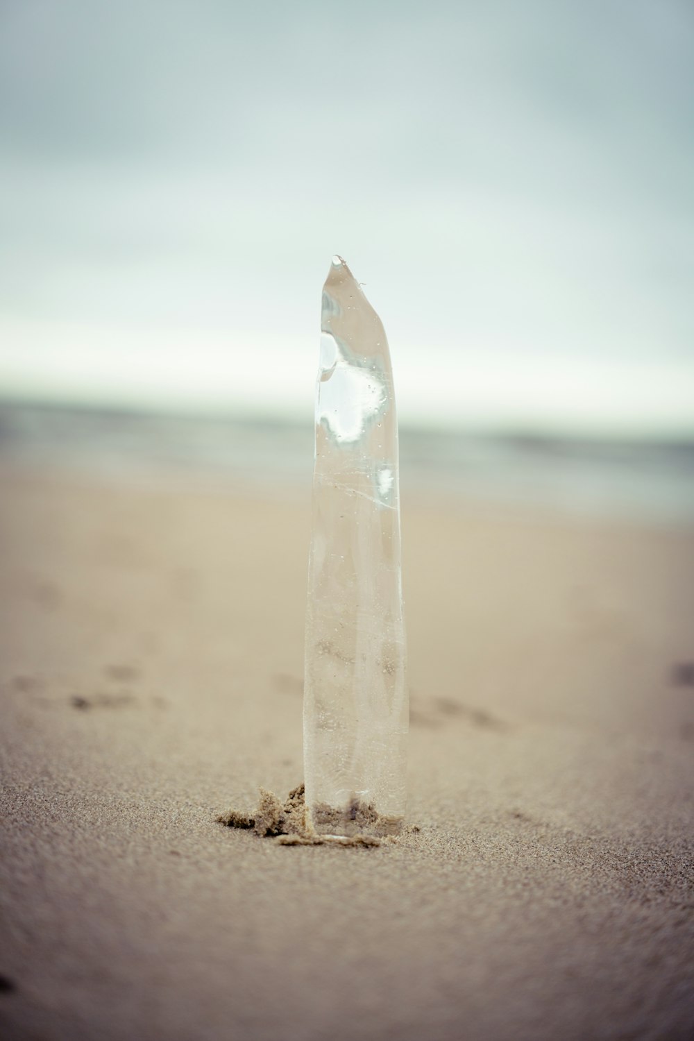 a broken glass bottle sitting on top of a sandy beach