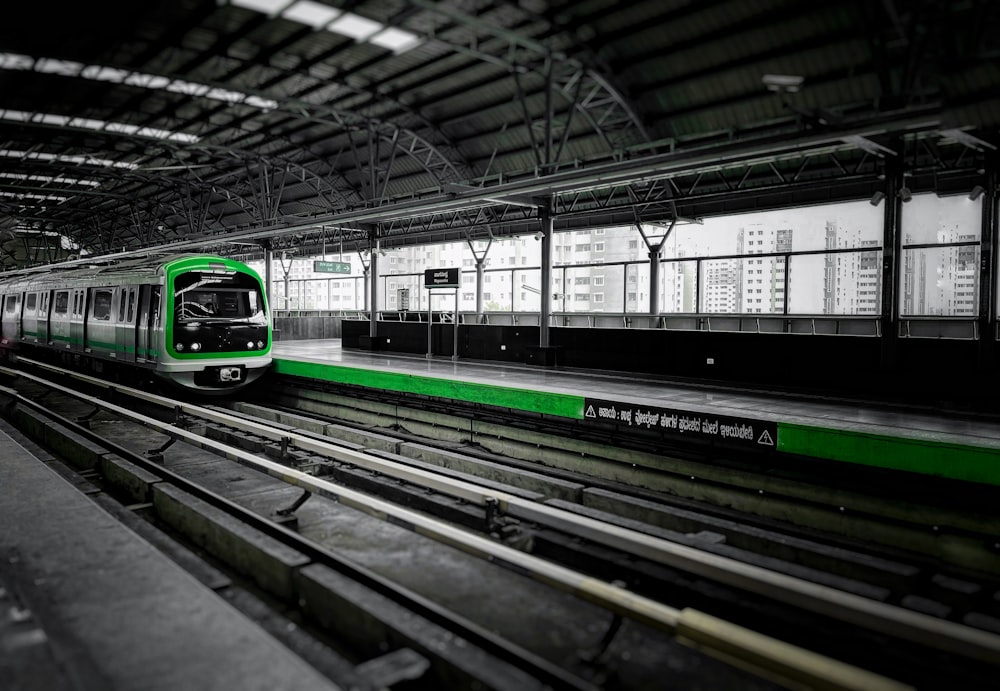 a green and white train pulling into a train station