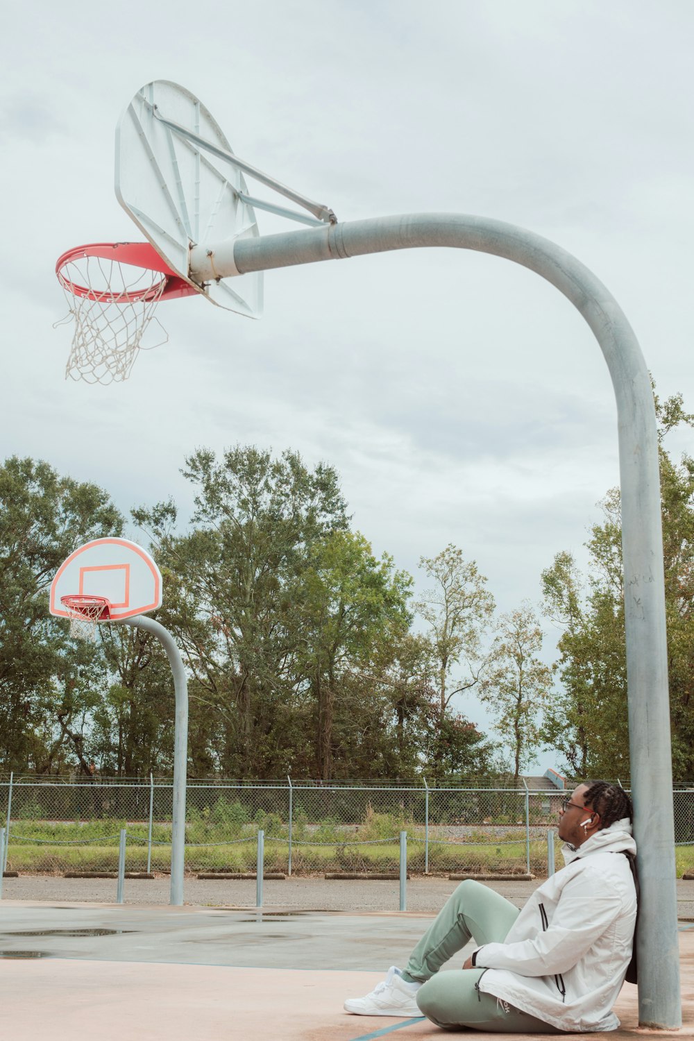 a man sitting on the ground next to a basketball hoop