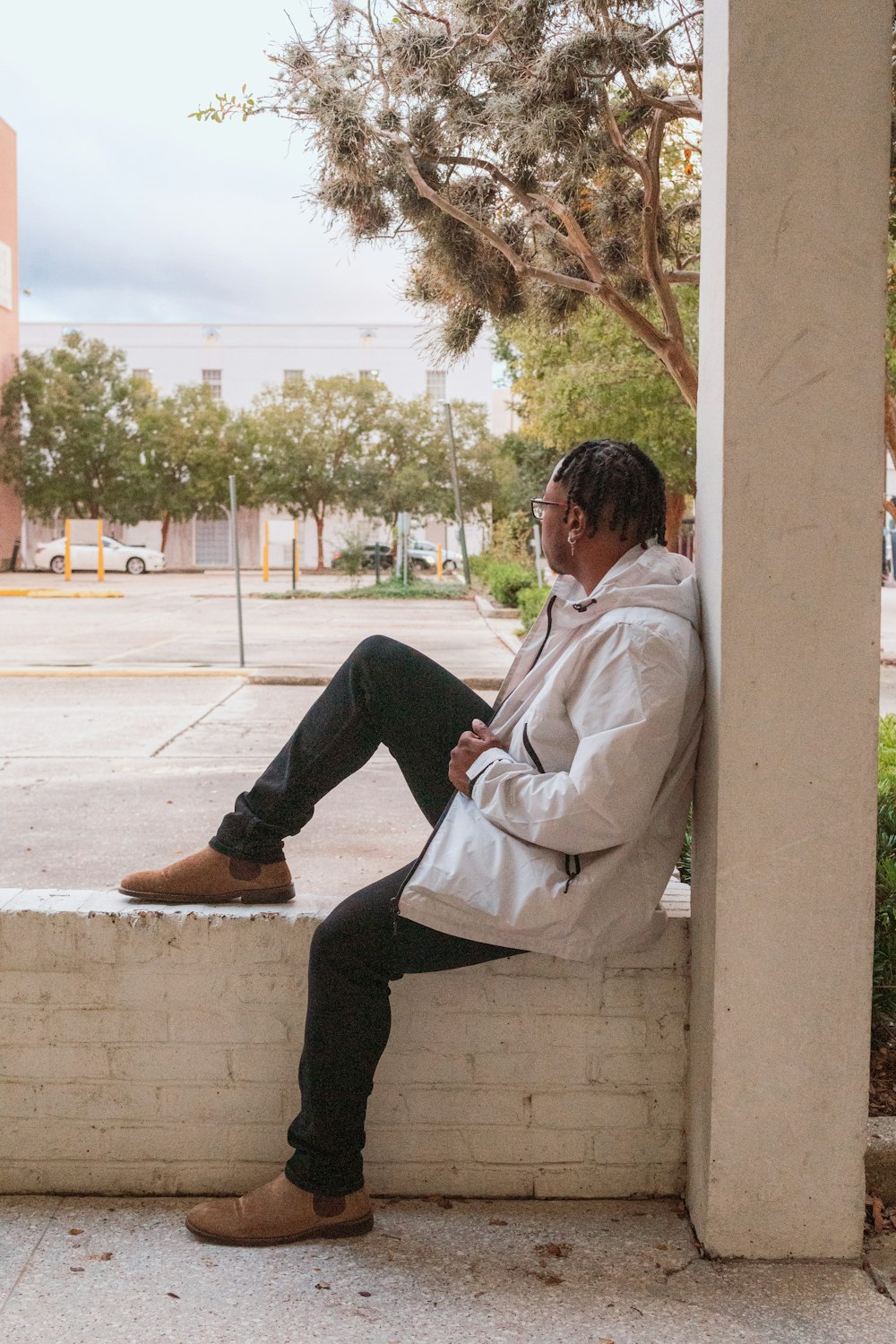 a man sitting on a ledge next to a tree