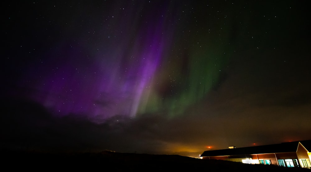 a purple and green light shines in the night sky