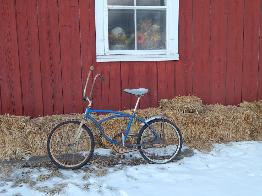 a blue bicycle parked in front of a red barn