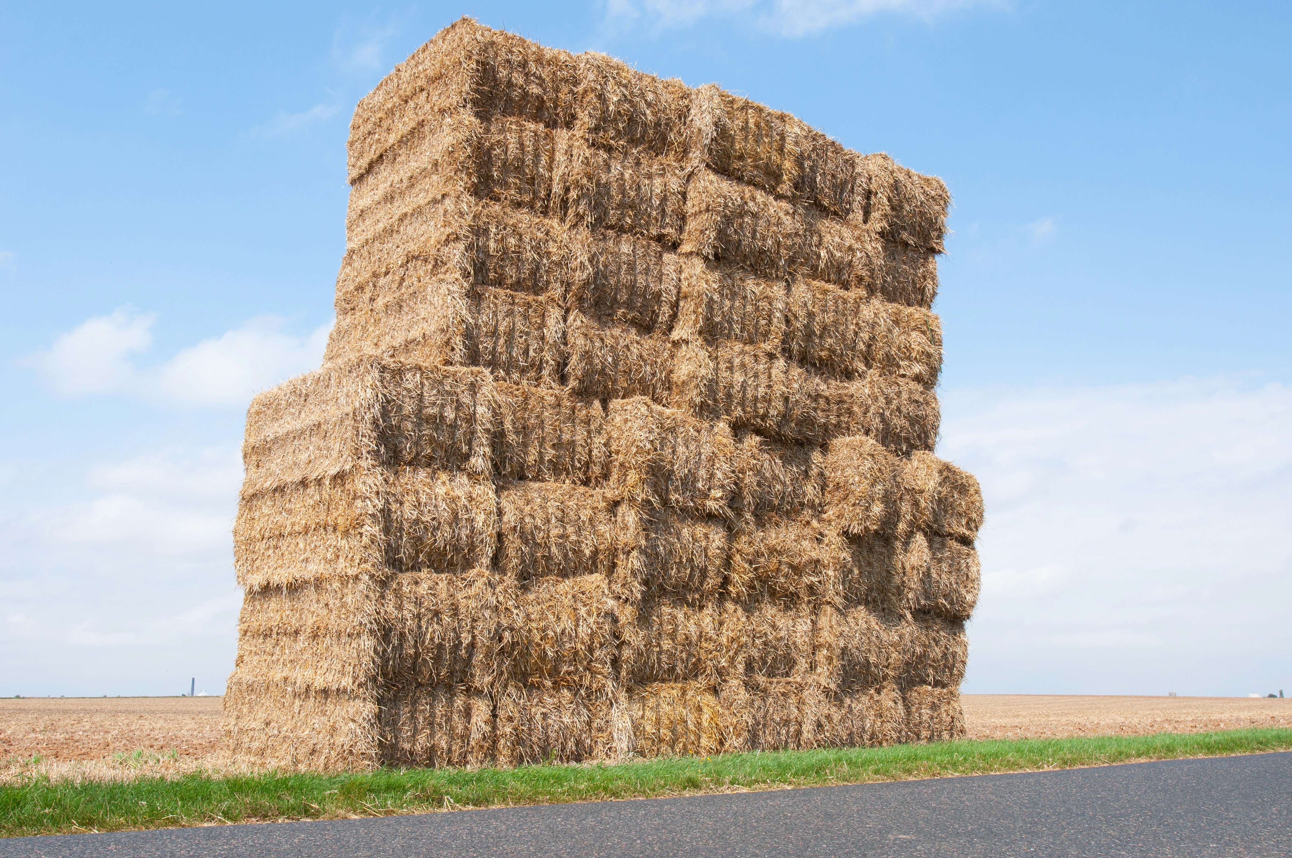 a large stack of hay sitting on the side of a road