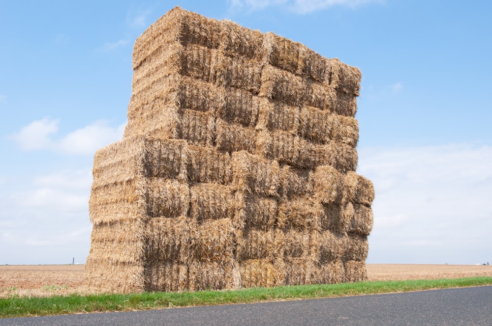 a large stack of hay sitting on the side of a road