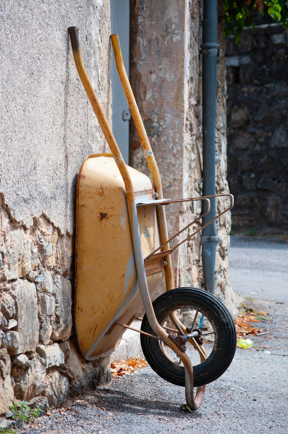 a wheelbarrow leaning up against a stone wall