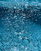 Close-up of sparkling clean pool water with bubbles rising to the surface.