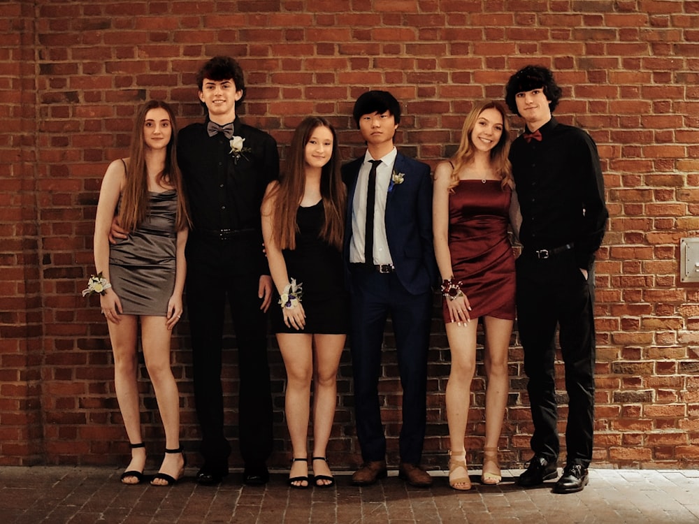 a group of people standing next to a brick wall