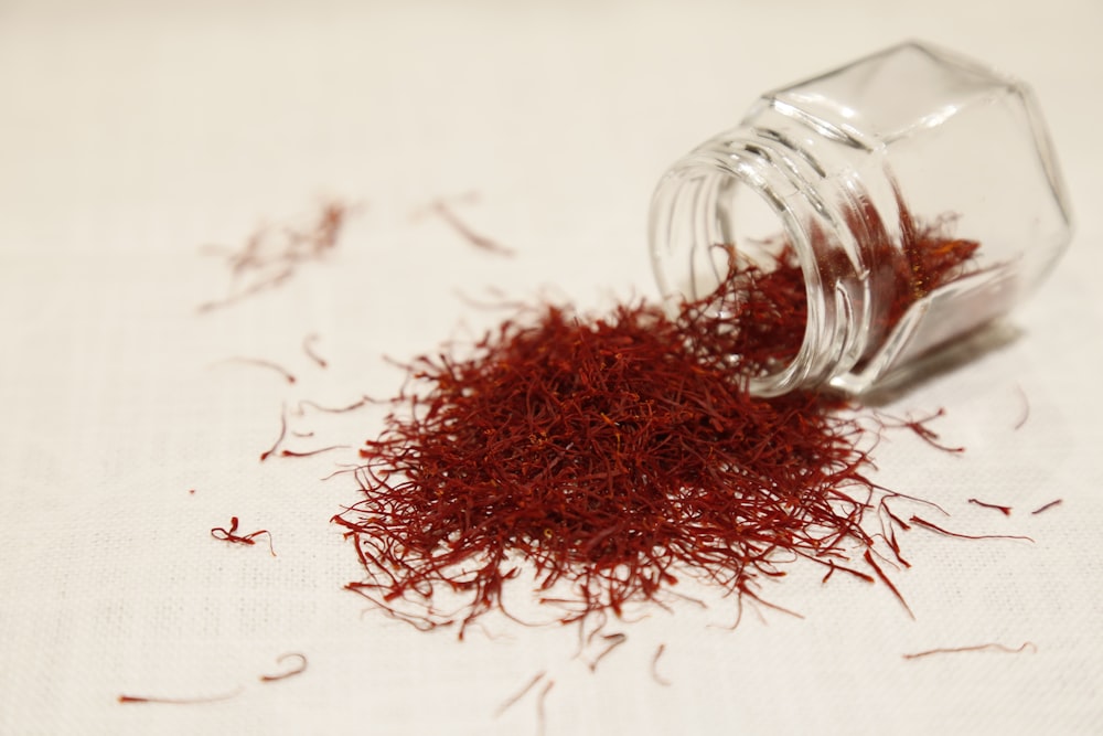 a glass jar filled with red stuff on top of a table