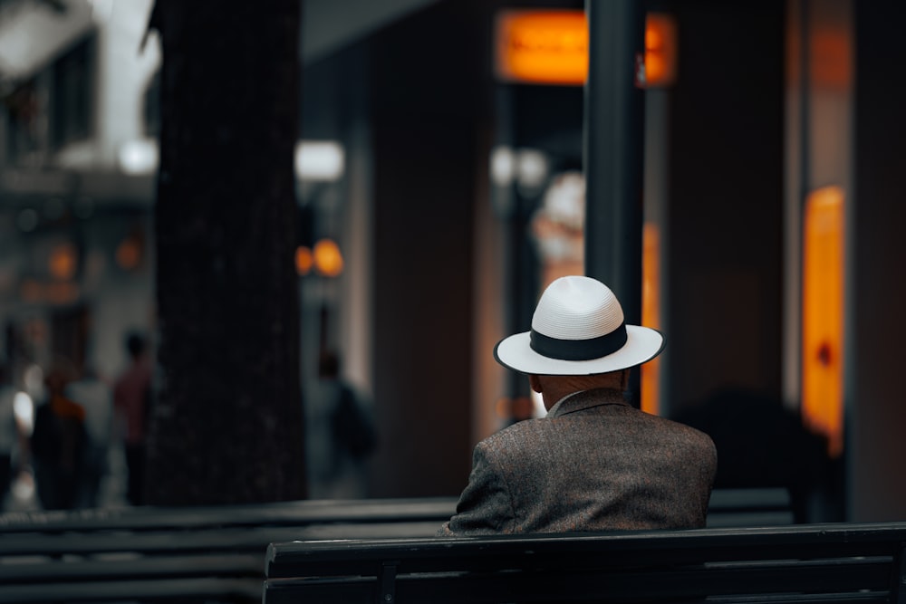 a man wearing a hat sitting on a bench