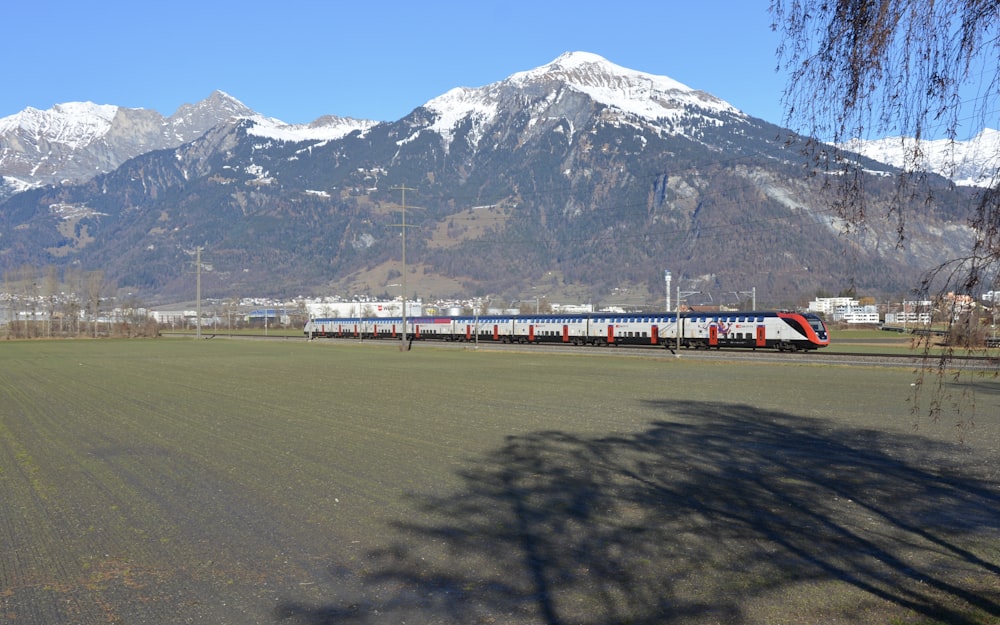a train traveling through a rural countryside with mountains in the background