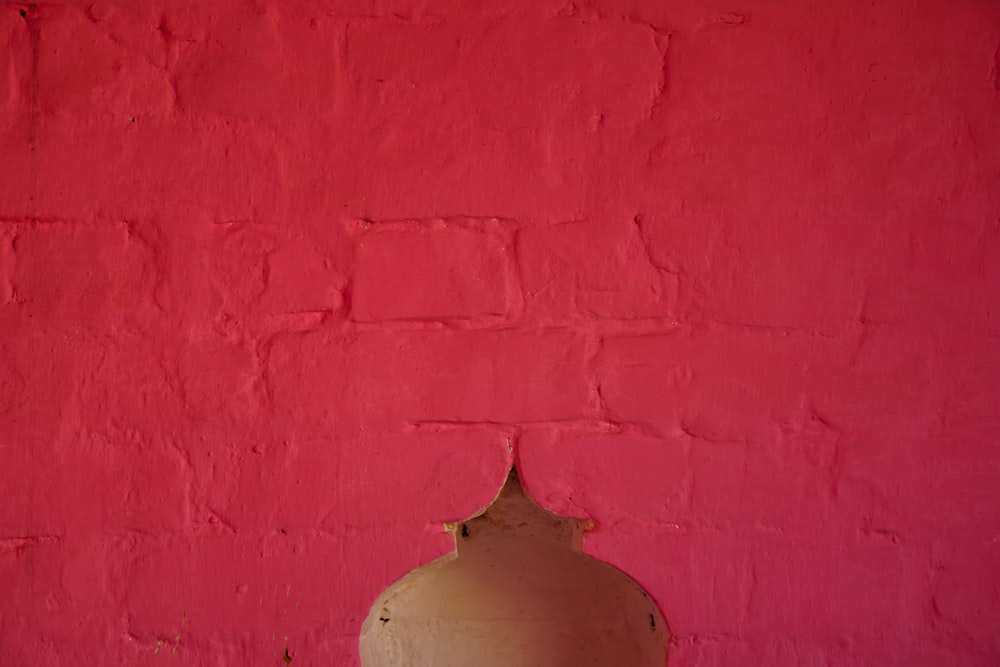 a red wall with a white vase on it