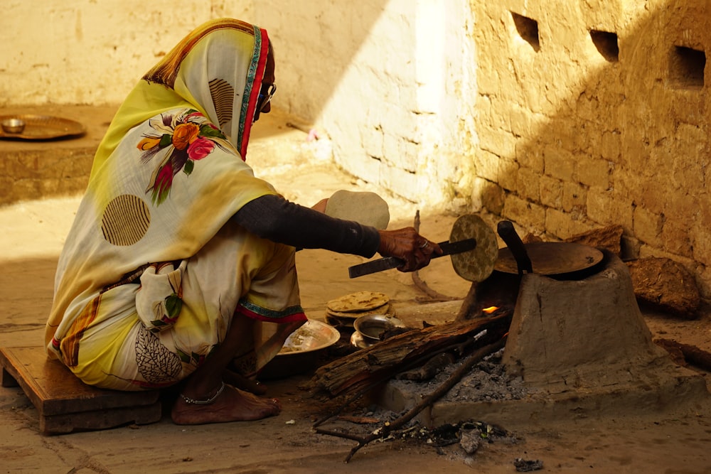 Una mujer en un sari amarillo y blanco está haciendo comida