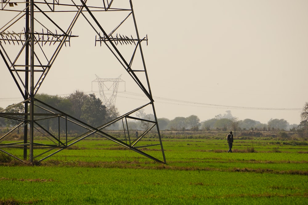 una persona in piedi in un campo sotto le linee elettriche