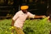 a man in a yellow turban is picking flowers