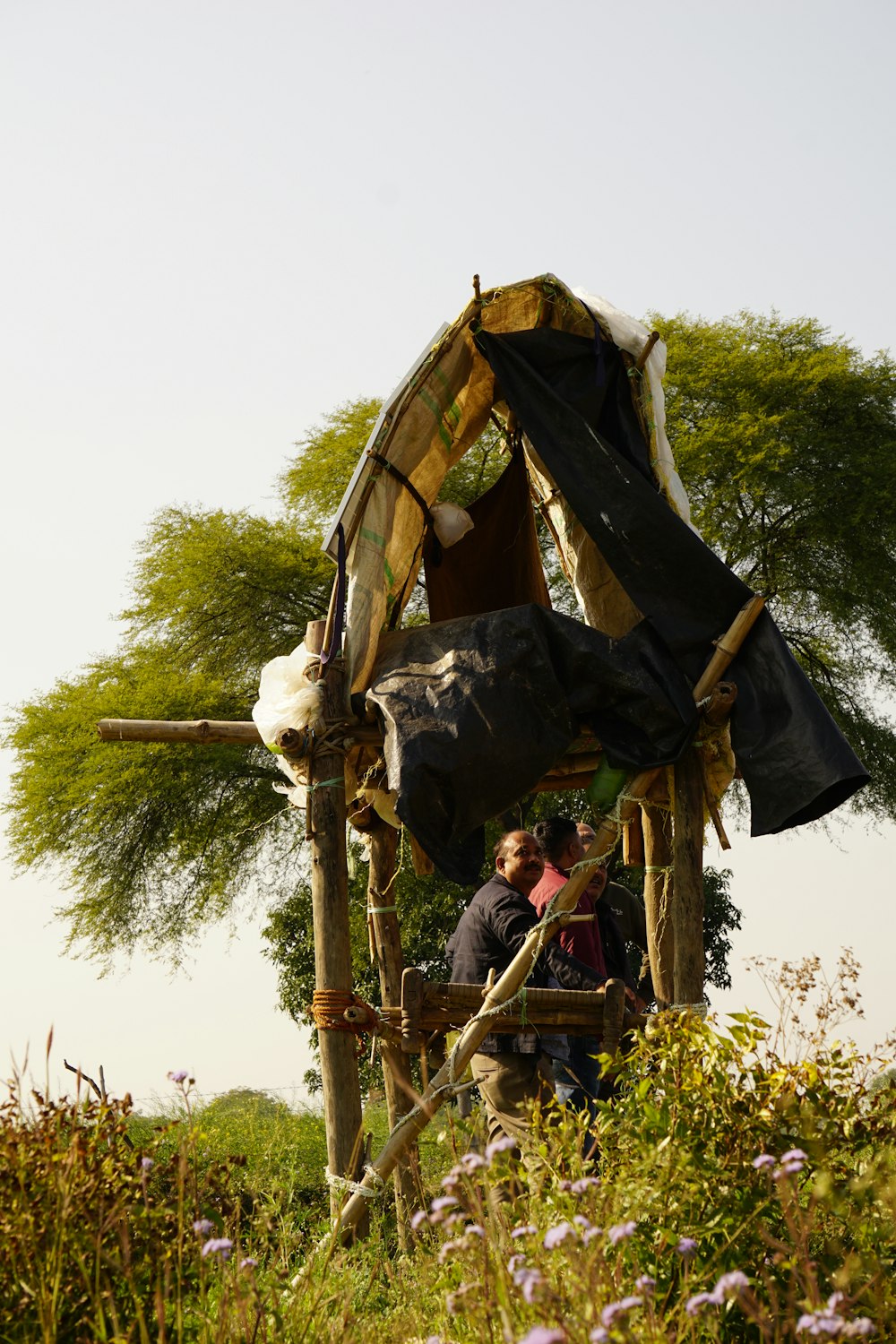 a couple of people standing next to a wooden structure