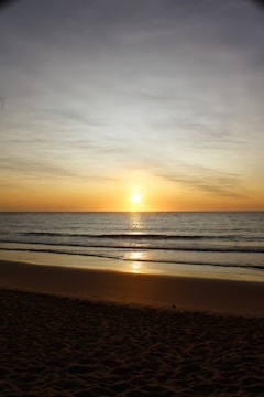 A stunning sunset over a calm ocean beach.