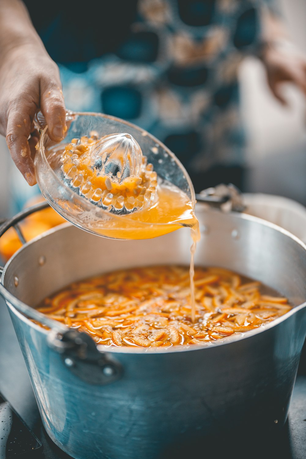 a person pouring something into a pot of food