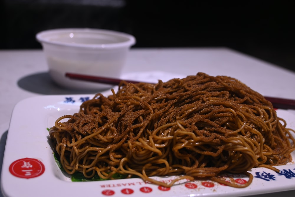 a plate of noodles and chopsticks on a table