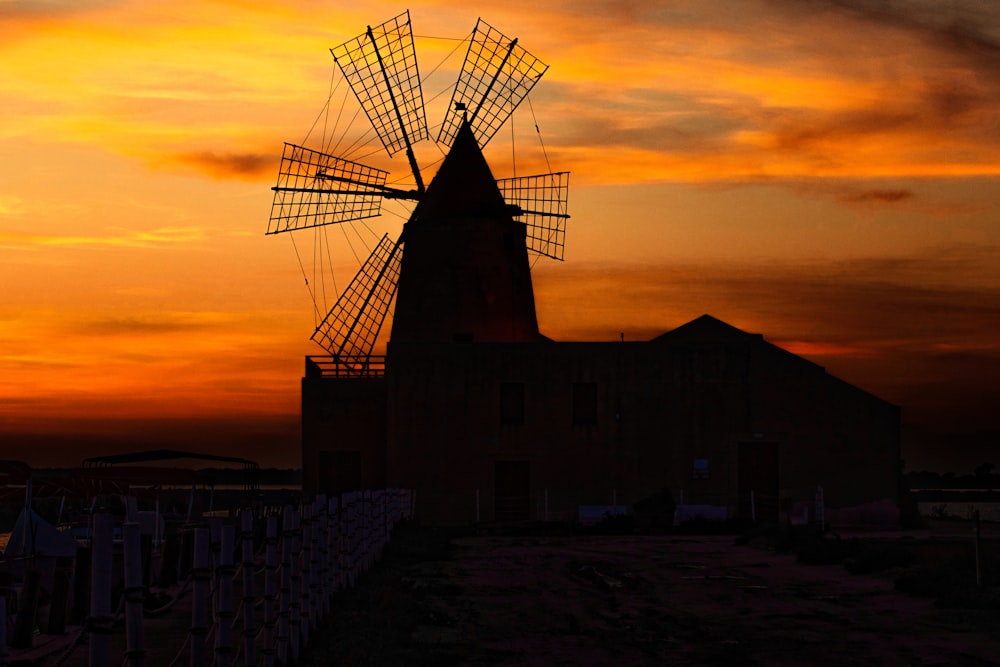 a windmill is silhouetted against a sunset sky