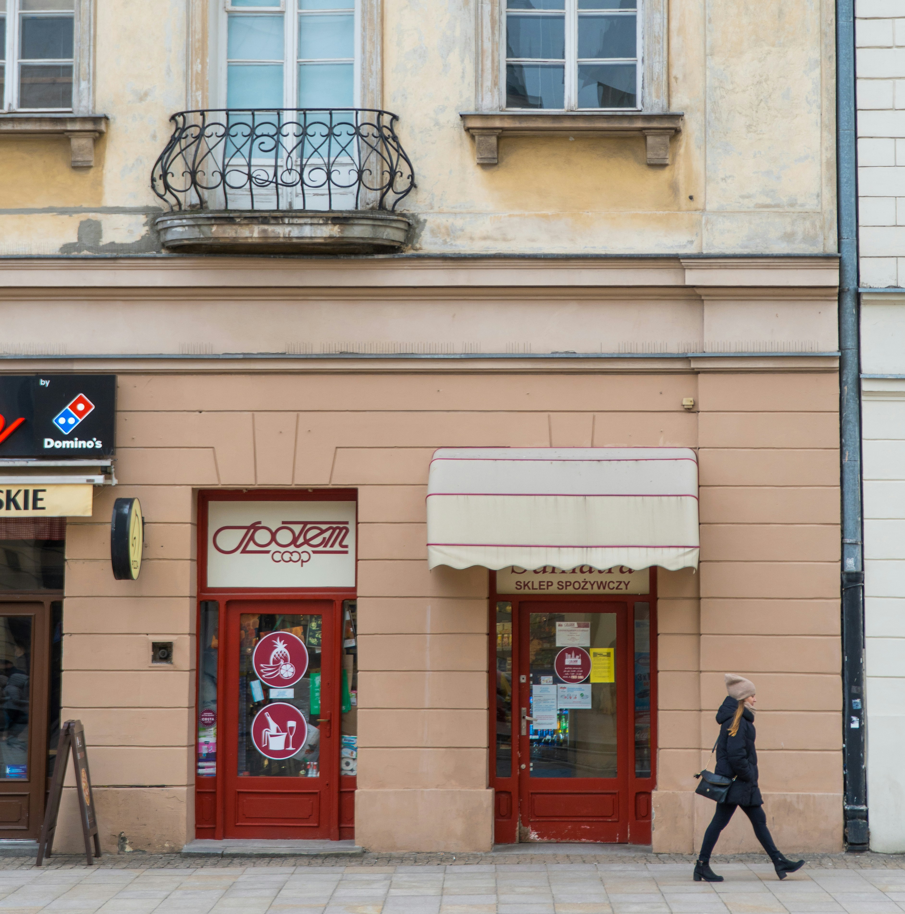 a woman walking down a street past a store