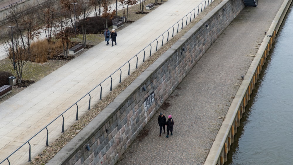 a group of people walking down a walkway next to a body of water