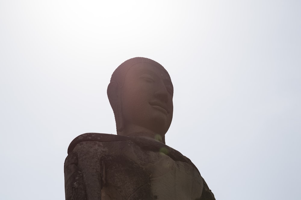 a statue of a person with a sky background
