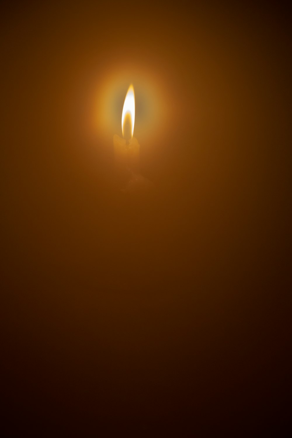 eine brennende Kerze im Dunkeln auf dunklem Hintergrund