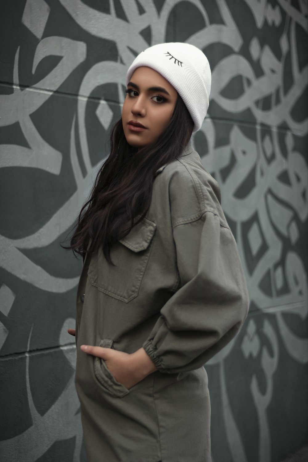 a woman wearing a white hat standing in front of a wall