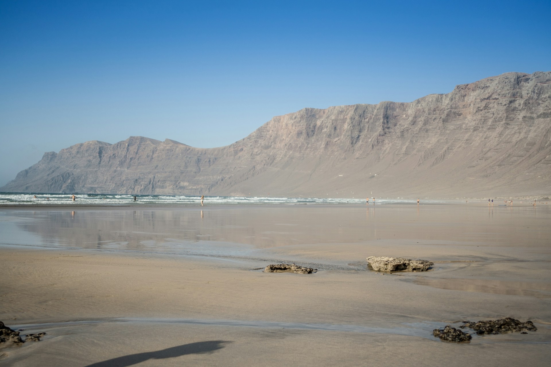 a person standing on a beach with a mountain in the background
