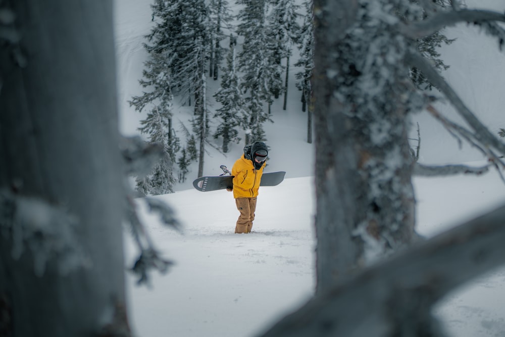 a person in a yellow jacket holding a snowboard