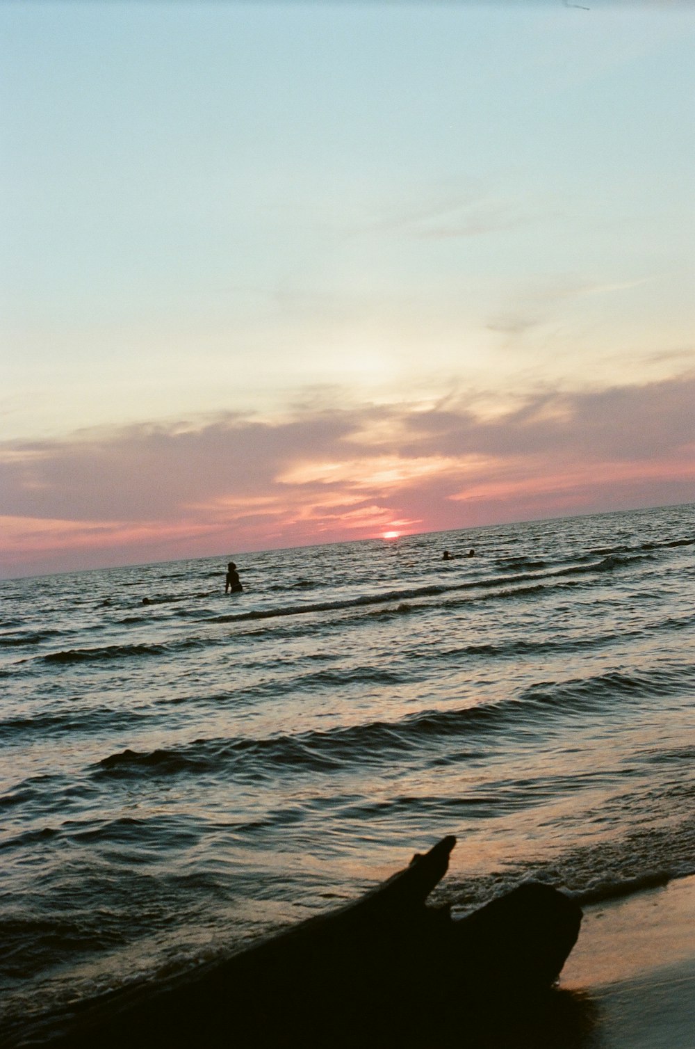 the sun is setting over the water at the beach