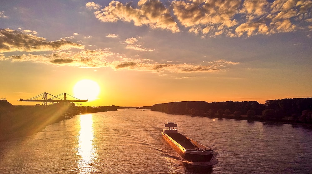 a boat traveling down a river at sunset