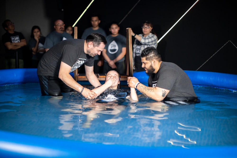 a group of people standing around a man in an inflatable pool