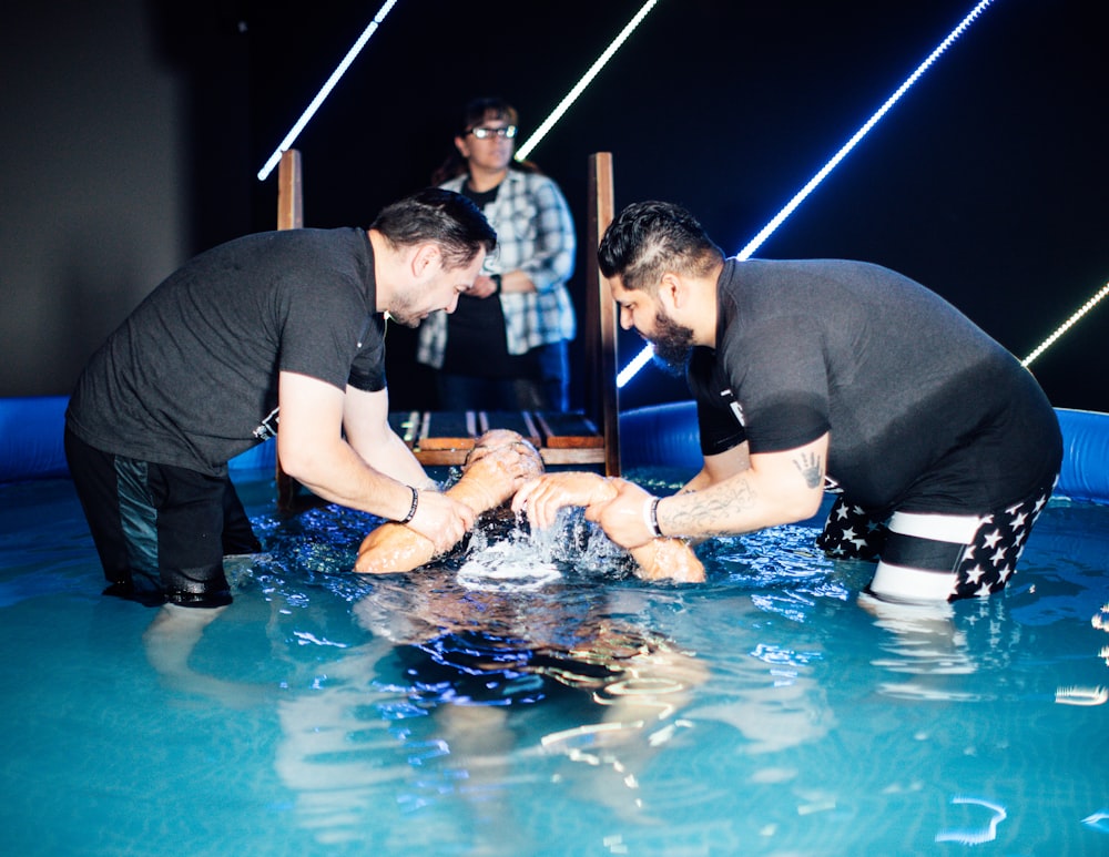 a couple of men standing next to each other in a pool