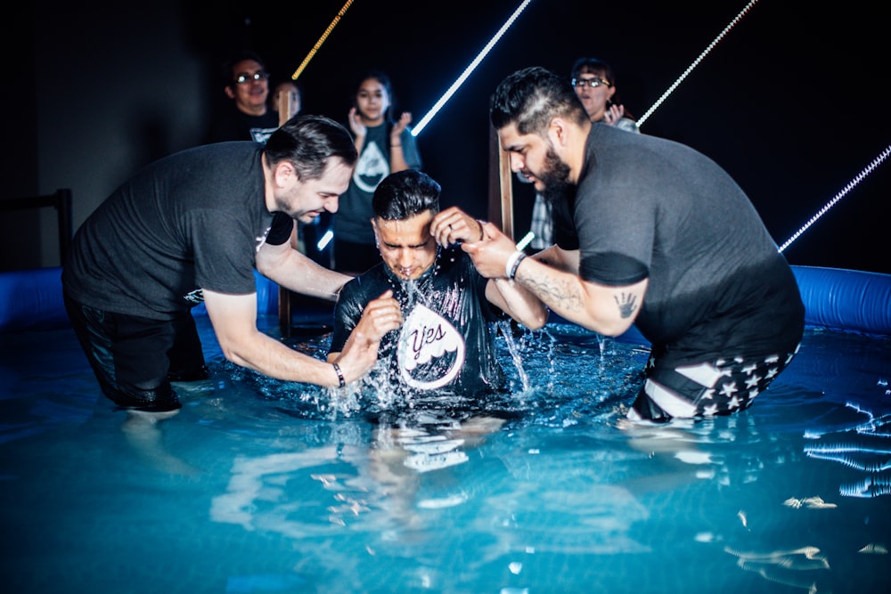 a group of men standing around a pool of water