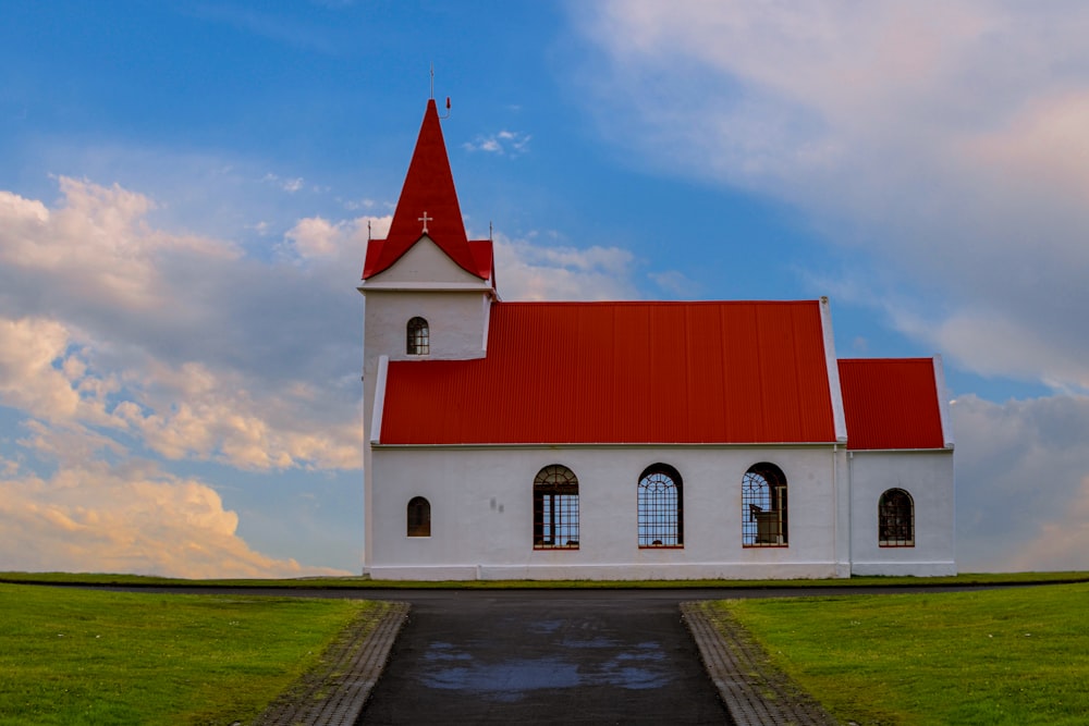 a white church with a red roof on a cloudy day