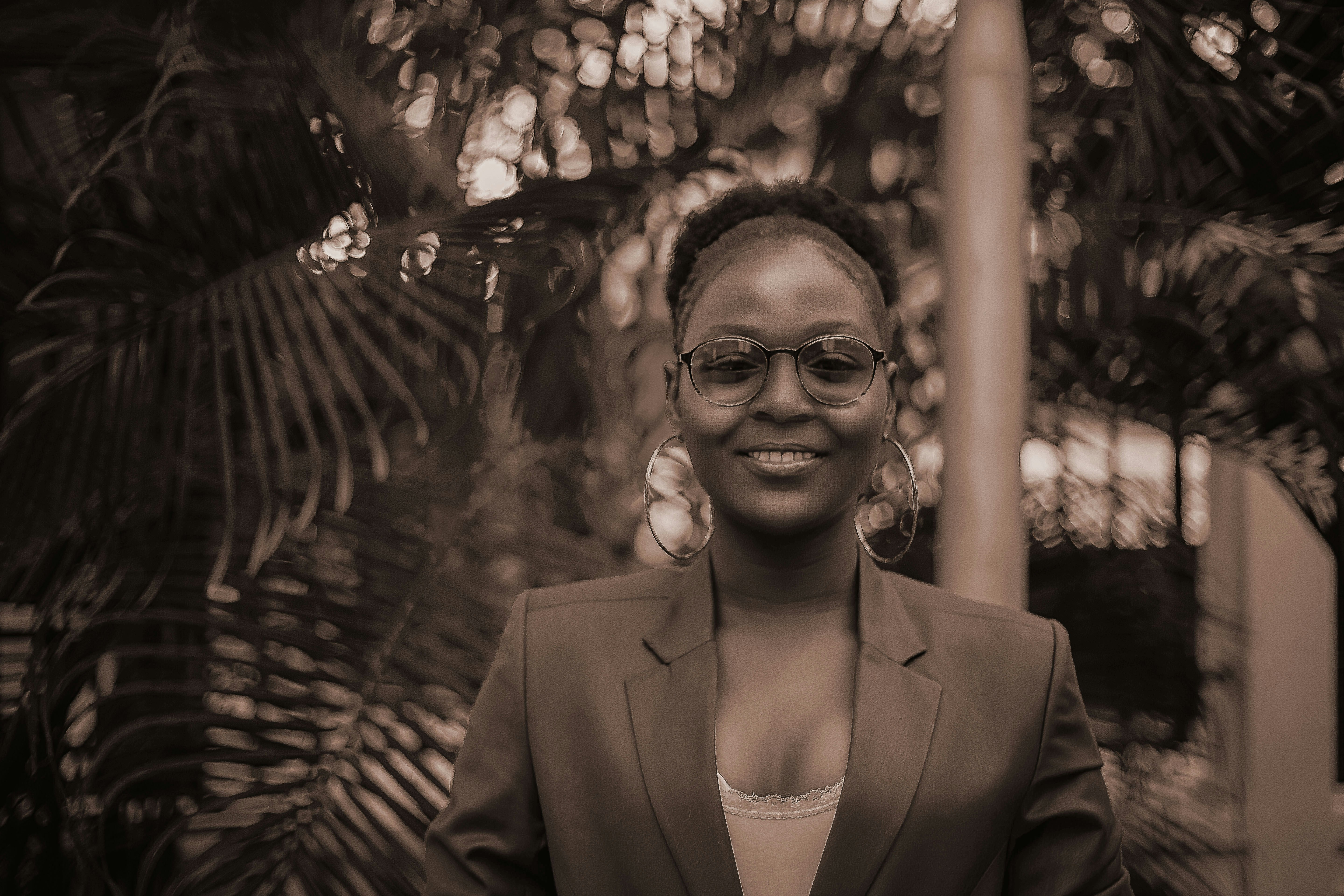 a woman wearing glasses standing in front of a palm tree