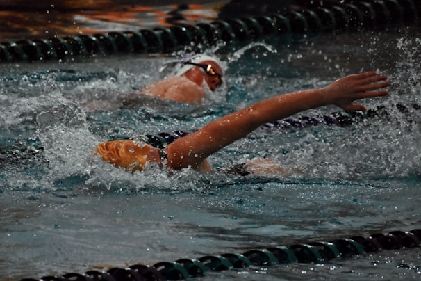 Close-up of a swimmer's hand slicing through water during a freestyle stroke in a competition pool.