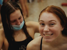 A group of young female water polo players smiling together by the poolside.