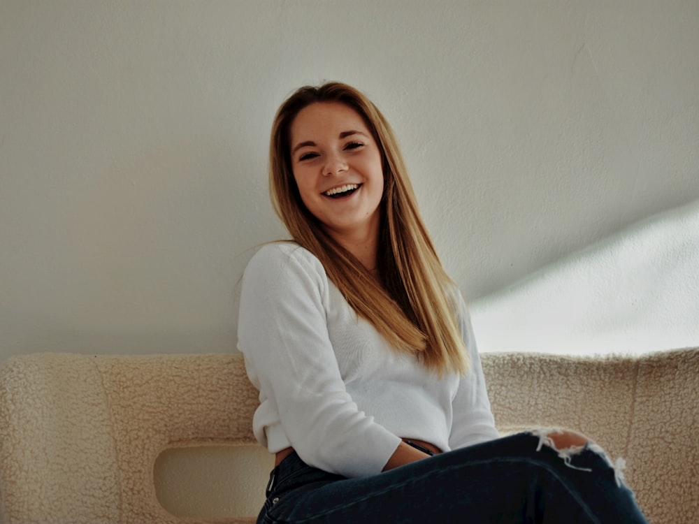 a woman sitting on a couch smiling at the camera