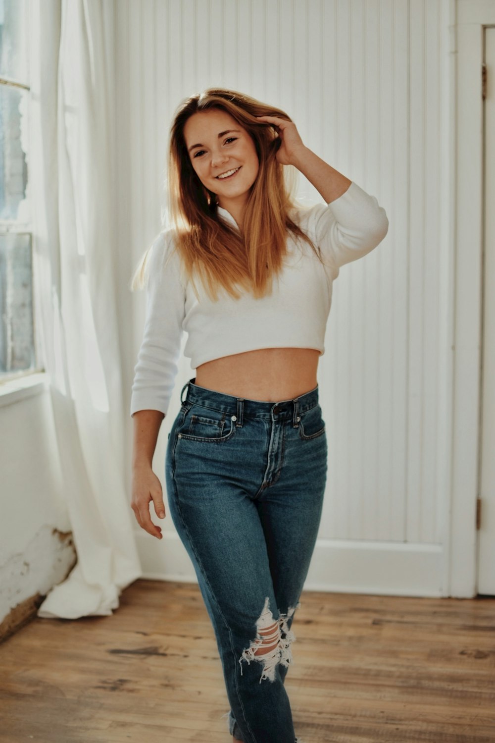a woman in a white top and jeans posing for a picture
