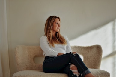 a woman sitting on top of a couch next to a window